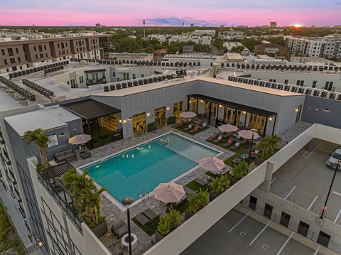 A rooftop pool area with a sunset in the background.