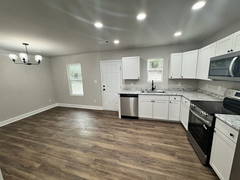 A kitchen with white cabinets and a wooden floor.