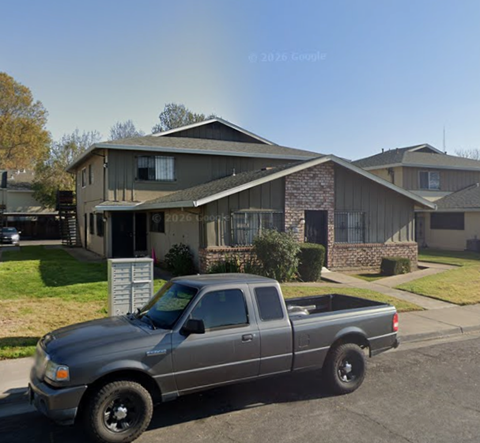 A silver pickup truck is parked in front of a house.