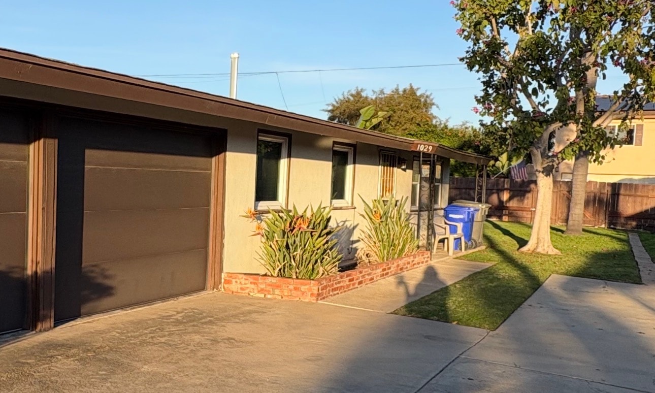 A house with a brown garage door and a blue trash bin.
