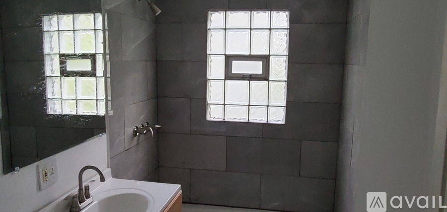 A bathroom with a sink, mirror, and two windows.