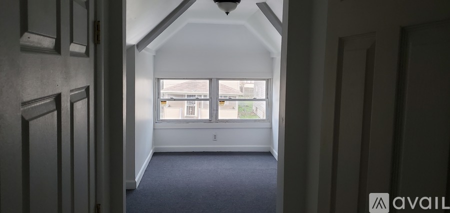 A hallway with a carpeted floor and a window with a view of a building outside.