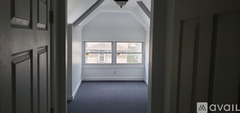A hallway with a carpeted floor and a window with a view of a building outside.