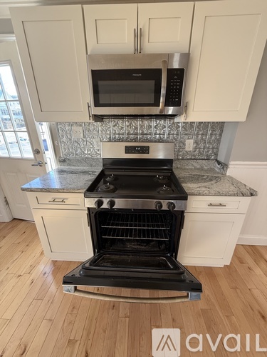 A kitchen with a black stove top oven and white cabinets.