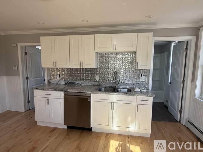A kitchen with white cabinets and a granite countertop.