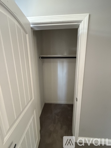 A small white closet with a shelf and a door.