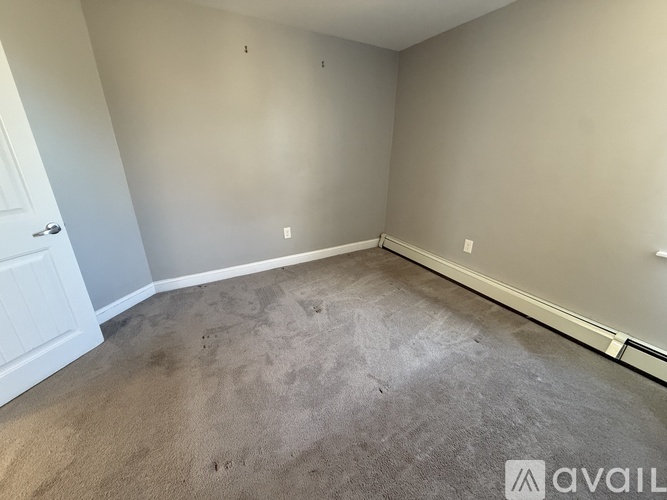 A room with a carpeted floor and a door on the left side.