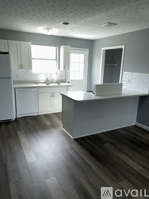 A kitchen with white cabinets and a wooden floor.