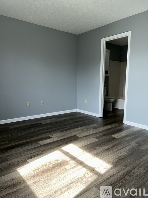 A room with wooden flooring and a doorway leading to another room.