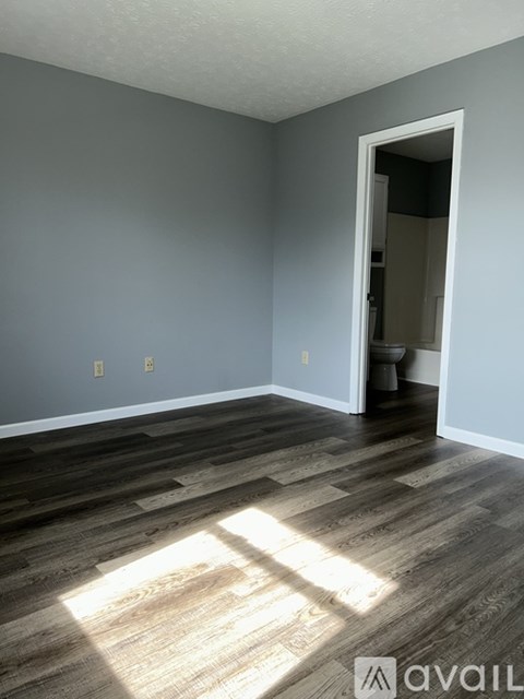 A room with wooden flooring and a doorway leading to another room.