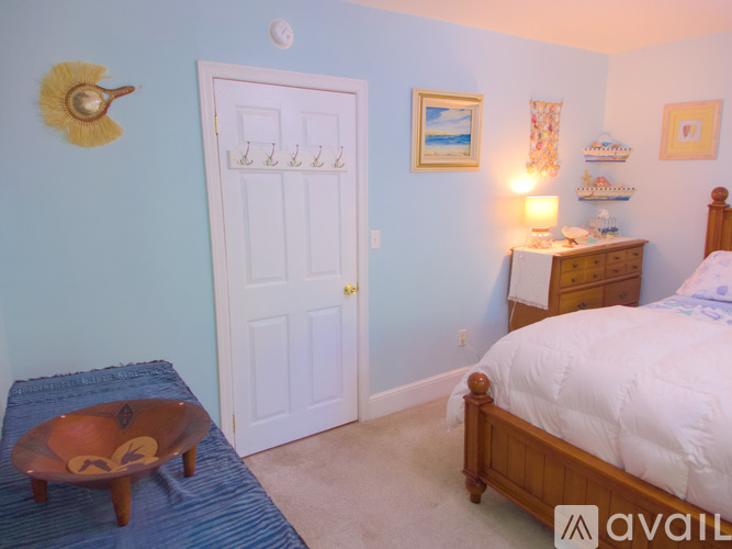 A bedroom with a bed, nightstand, and a door.