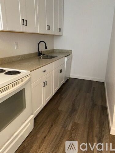 A kitchen with white cabinets and a stove top oven.