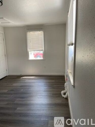 A room with a window and a wooden floor.