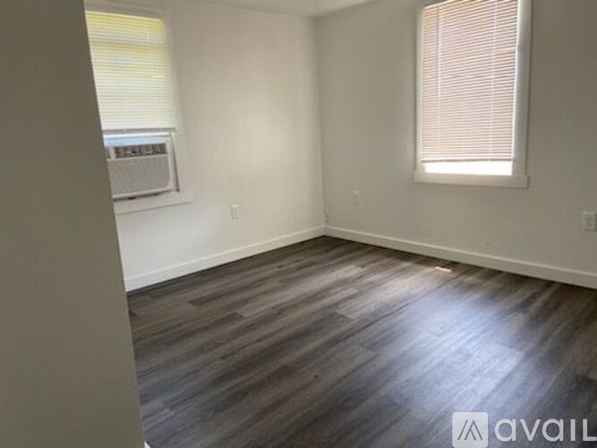 A room with wooden flooring and a window with blinds.