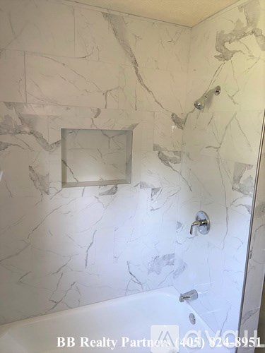 A bathroom with marble walls and a shower.