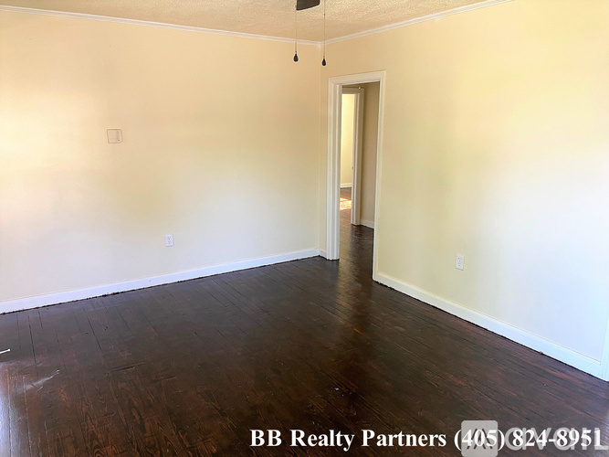 A room with a wooden floor and a doorway leading to another room.