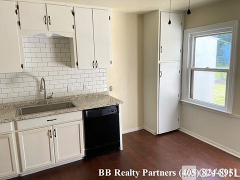 A kitchen with white cabinets and a black dishwasher.