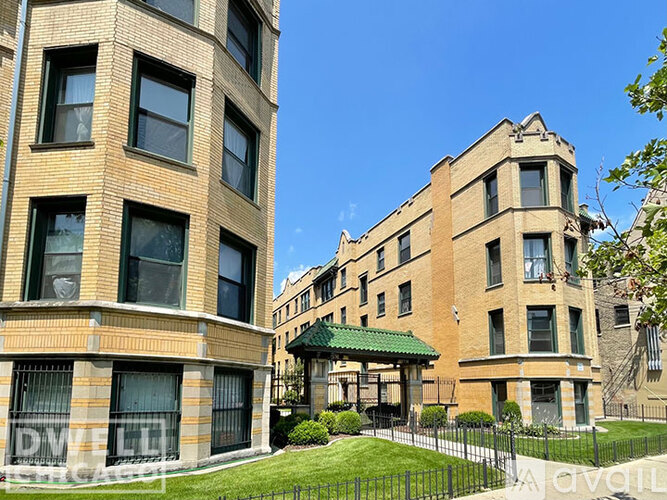 A large building with a green roof is situated between two smaller buildings.