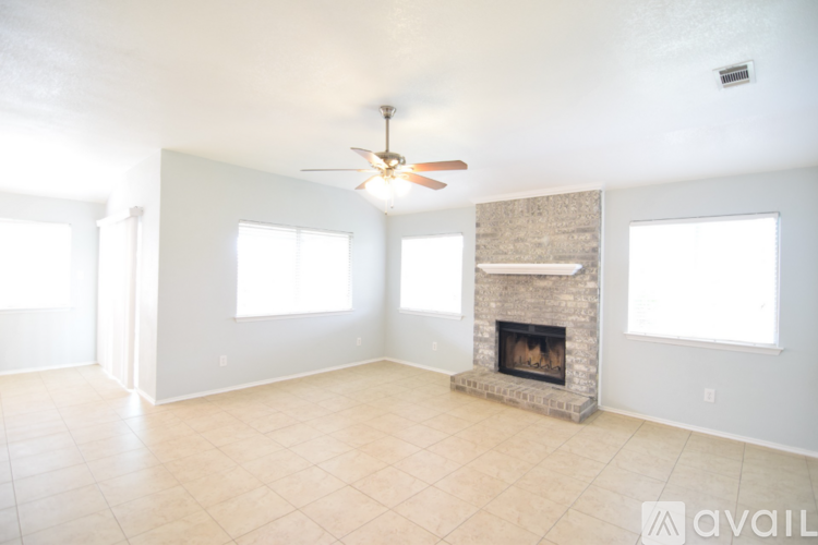 A spacious living room with a fireplace and a ceiling fan.