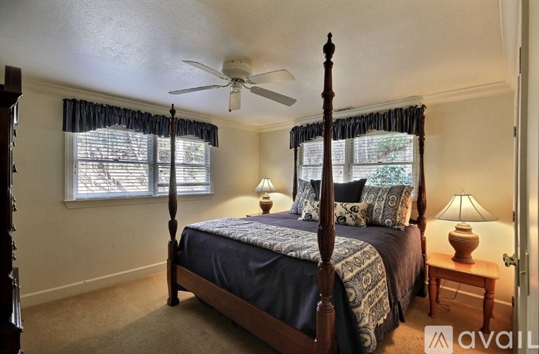 A bedroom with a four poster bed and a ceiling fan.