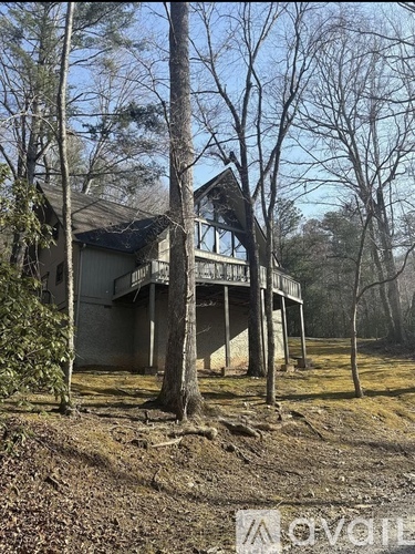 A house with a porch and a tree in front of it.