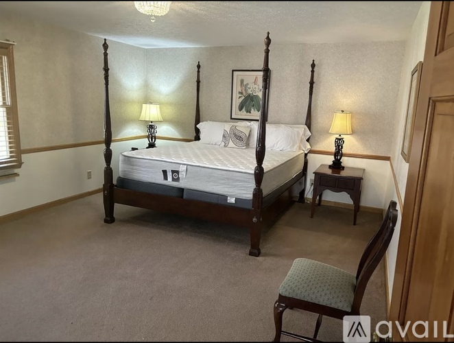 A bedroom with a four poster bed and two lamps.