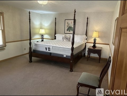A bedroom with a four poster bed and two lamps.