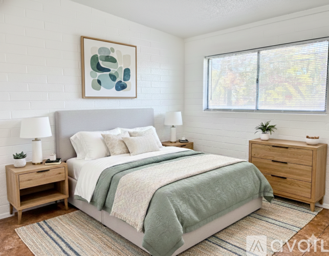 A bedroom with a bed, nightstands, and a framed artwork on the wall.