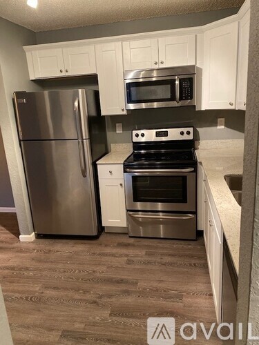 A kitchen with a stainless steel refrigerator, microwave, oven, and cabinets.
