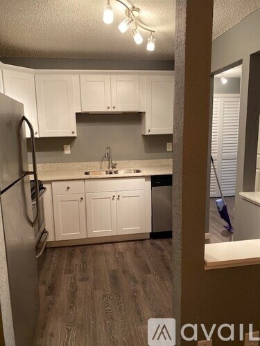 A kitchen with white cabinets and a black refrigerator.