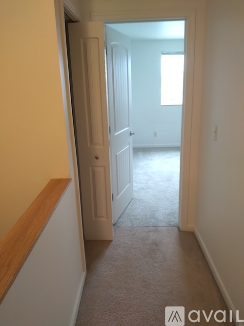 A hallway with a carpeted floor and a door on the right.