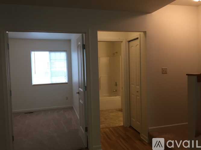 A bathroom with a tub and a window is visible from a hallway.