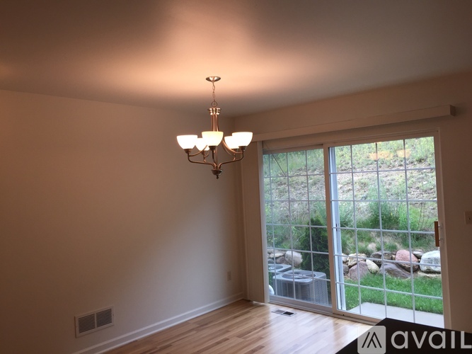 A room with a chandelier and a window overlooking a rock garden.