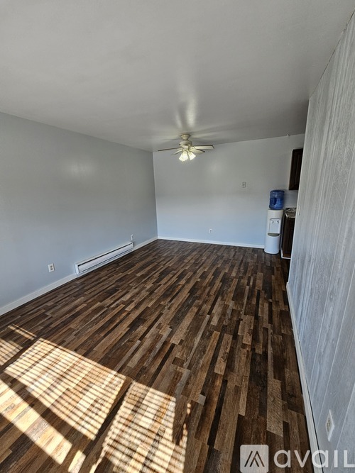 A room with wooden flooring and a ceiling fan.