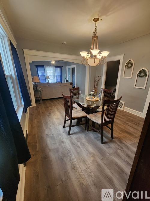 A dining room with a table set for four and a chandelier hanging from the ceiling.