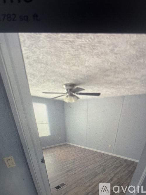 A room with a ceiling fan and wooden flooring.