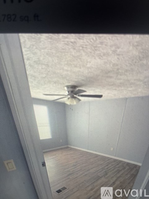 A room with a ceiling fan and wooden flooring.