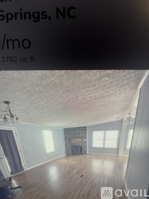 A room with a wood floor and a stone fireplace is available for rent in Spring, NC.