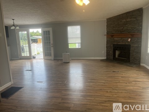 A living room with wood flooring and a stone fireplace.