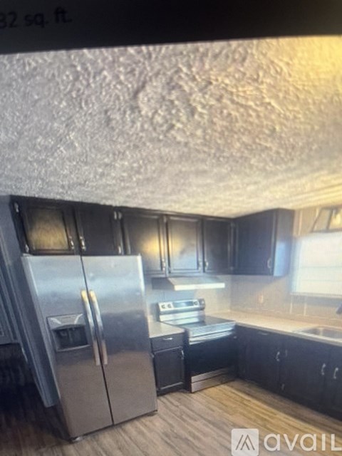 A kitchen with a stainless steel refrigerator and black cabinets.
