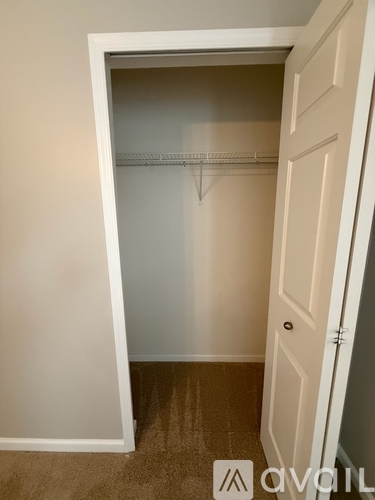 A white door is open to a room with a carpeted floor and a wall.