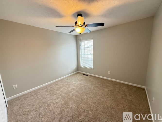 A room with a ceiling fan and carpeted floor.