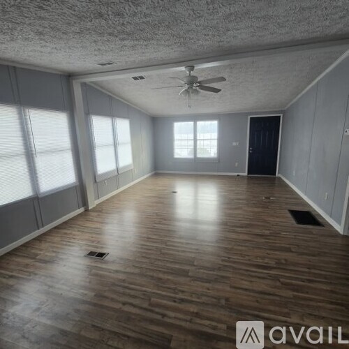 A spacious room with wooden flooring and a ceiling fan.