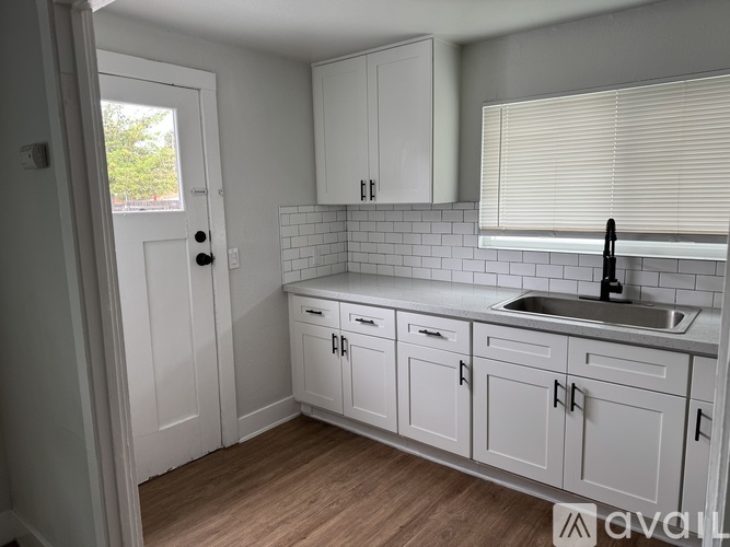 A kitchen with white cabinets and a wooden floor.
