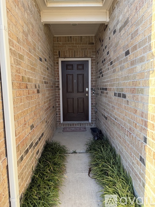 A door is at the end of a hallway with brick walls on either side.