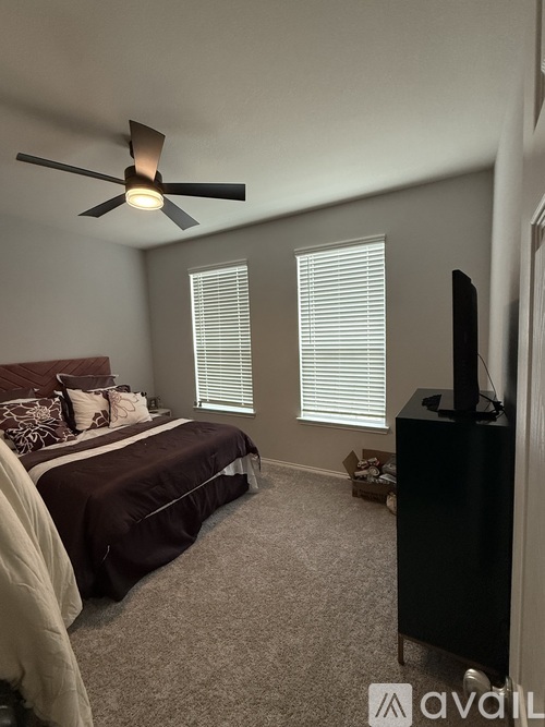 A bedroom with a bed, a ceiling fan, and a television.