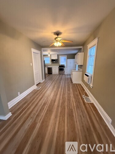 A long hallway with wood floors and a ceiling fan.