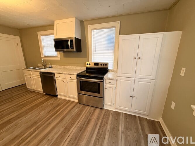 A kitchen with white cabinets and a wooden floor.