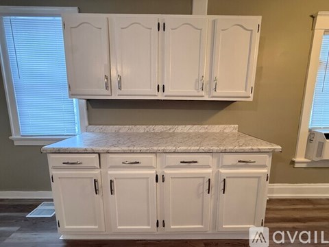 A kitchen with white cabinets and a marble countertop.