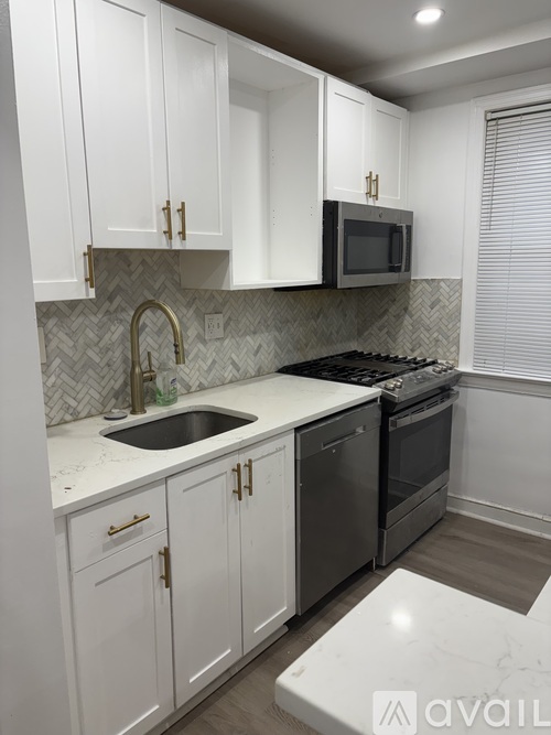 A kitchen with white cabinets and a black microwave above the stove.